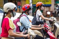 mulheres em motos usando máscaras de proteção em Hanoi, no Vietnã